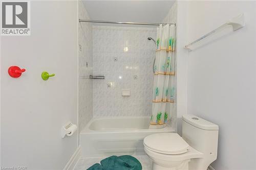 Bathroom featuring a white bathtub, tiled shower surround, and a white toilet - 4267 Sarazen Drive, Burlington, ON - Indoor Photo Showing Bathroom