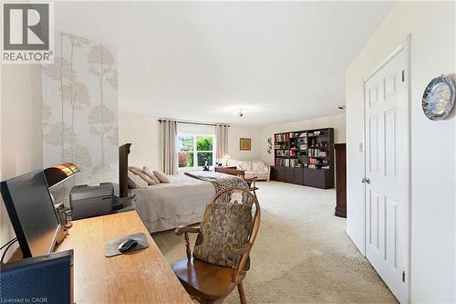 Spacious room featuring light-colored carpeting, a partial accent wall with tree-patterned wallpaper, and a large window with exterior foliage visible, the fp has not been used.  There are 2 large wal - 10 Huisman Lane, Hamilton, ON - Indoor