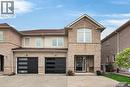 Stone and stucco facade featuring a prominent gable, arched window, two distinct garage doors with horizontal glass panels, and a covered entry - 4236 Prudham Avenue, Burlington, ON  - Outdoor With Facade 