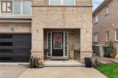 Brick and stone facade featuring a recessed entry, black front door with sidelights, and an attached garage with contemporary horizontal window inserts - 4236 Prudham Avenue, Burlington, ON - Outdoor With Exterior