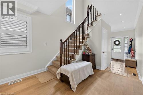 Hardwood flooring throughout the main level featuring a carpeted staircase with dark wood banister and white balusters - 4236 Prudham Avenue, Burlington, ON - Indoor Photo Showing Other Room