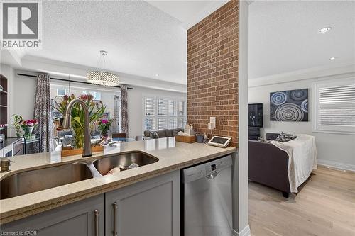 Kitchen island featuring a double basin stainless steel sink with a gooseneck faucet, light granite-style countertop, and integrated dishwasher - 4236 Prudham Avenue, Burlington, ON - Indoor Photo Showing Kitchen With Double Sink