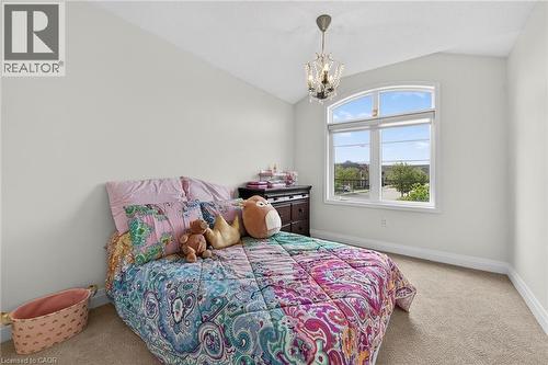 Vaulted ceiling room featuring an arched top window, a crystal chandelier, light neutral-toned walls, and carpet flooring - 4236 Prudham Avenue, Burlington, ON - Indoor Photo Showing Bedroom