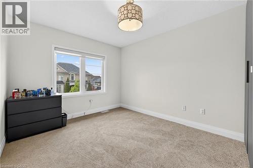 Carpeted room with a bright window, crown molding, and a decorative ceiling light fixture - 4236 Prudham Avenue, Burlington, ON - Indoor