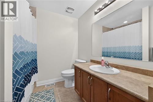 Bathroom featuring a spacious vanity with integrated sink, wood-finish cabinetry, and a large mirror - 4236 Prudham Avenue, Burlington, ON - Indoor Photo Showing Bathroom