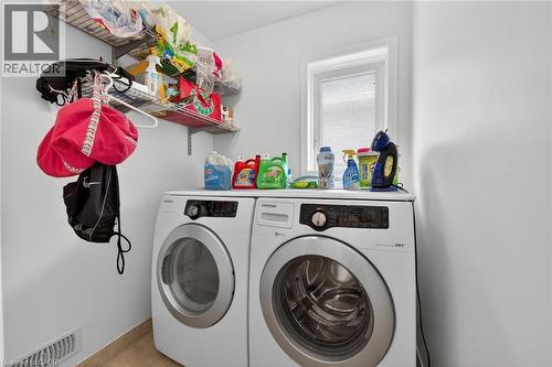 Dedicated laundry area featuring a front-loading washer and dryer set, white walls, light-toned tile flooring, and a window - 4236 Prudham Avenue, Burlington, ON - Indoor Photo Showing Laundry Room