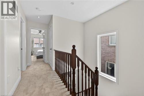 Carpeted hallway with a dark wood staircase railing, recessed lighting, and a transom window - 4236 Prudham Avenue, Burlington, ON - Indoor Photo Showing Other Room