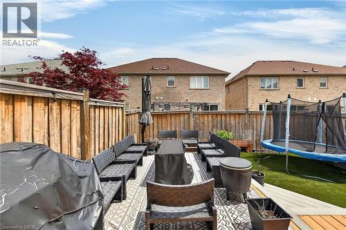 Expansive backyard featuring a multi-level deck with patterned outdoor rug, fenced perimeter, and a distinct artificial turf area - 4236 Prudham Avenue, Burlington, ON - Outdoor With Deck Patio Veranda