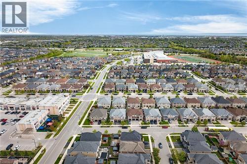 Expansive aerial perspective showcasing a residential development with numerous single-family homes, commercial structures, and a large recreational field - 4236 Prudham Avenue, Burlington, ON - Outdoor With View