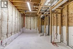 Unfinished basement space featuring exposed wood framing, concrete flooring, and insulated walls, offering customization potential - 