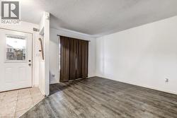Spacious room with wood-finish flooring and a large window featuring full-length curtains - 