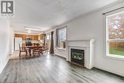 Expansive living area with wood-finish flooring, a white mantel fireplace, and large windows - 