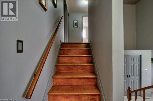 Staircase featuring wood-finish treads and a matching wood-finish handrail, complemented by light grey wall paint - 34 Westwood Crescent, Kitchener, ON - Indoor Photo Showing Other Room