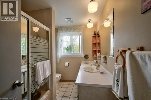 Bathroom featuring a single vanity with an integrated sink, a large mirror, a window with natural light, a toilet, and a shower with frosted glass - 34 Westwood Crescent, Kitchener, ON - Indoor Photo Showing Bathroom