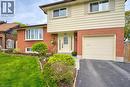 Split-level residence featuring a brick and siding exterior, an integrated garage, a bay window, and a well-maintained lawn with landscaping - 34 Westwood Crescent, Kitchener, ON  - Outdoor With Exterior 