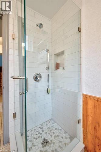 Glass-enclosed shower featuring white subway tile walls, a mosaic tile floor, built-in shower niche, and a polished chrome shower system with a grab bar - 34 Westwood Crescent, Kitchener, ON - Indoor Photo Showing Bathroom