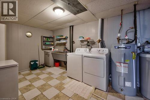 Utility room featuring checkerboard flooring, a utility sink, and wall-mounted shelving - 34 Westwood Crescent, Kitchener, ON - Indoor Photo Showing Laundry Room