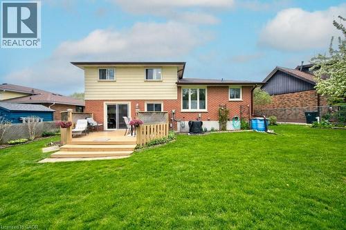 Expansive backyard featuring a multi-level wood deck with lattice accents, a sliding glass door entry, and a broad green lawn - 34 Westwood Crescent, Kitchener, ON - Outdoor