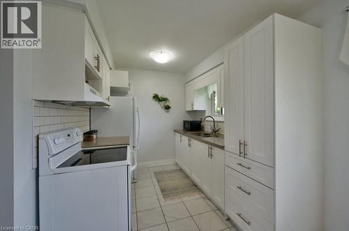 Contemporary kitchen featuring white shaker-style cabinetry, a white subway tile backsplash, and a built-in range - 34 Westwood Crescent, Kitchener, ON - Indoor Photo Showing Laundry Room