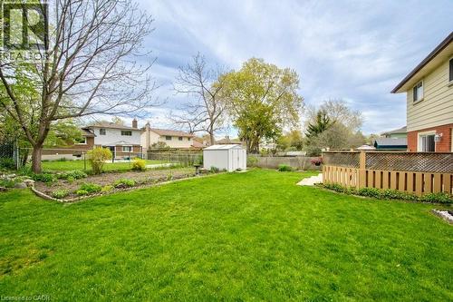 Expansive backyard featuring a manicured lawn, established garden beds, a shed, a wooden privacy fence, and mature trees - 34 Westwood Crescent, Kitchener, ON - Outdoor