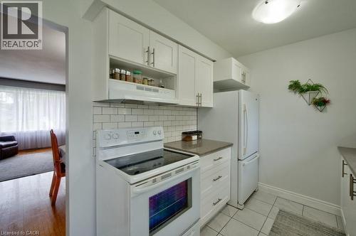 Kitchen featuring white shaker-style cabinetry with brushed nickel pulls, white subway tile backsplash, and light-toned countertop - 34 Westwood Crescent, Kitchener, ON - Indoor Photo Showing Kitchen