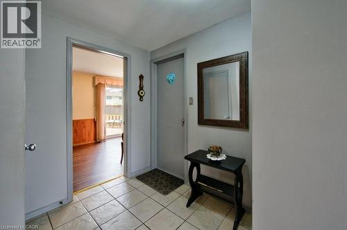 Tiled entry flooring featuring a light-toned finish, a framed mirror, and a wall-mounted decorative clock - 34 Westwood Crescent, Kitchener, ON - Indoor Photo Showing Other Room