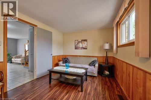 Living area featuring wood-finish flooring, half-wall wood paneling, and a white-framed window - 34 Westwood Crescent, Kitchener, ON - Indoor