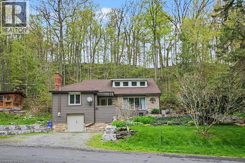 Exterior featuring stone and siding finishes, a single-car garage, a dormer with multiple windows, and a prominent brick chimney - 1333 Hidden Valley Road, Burlington, ON - Outdoor