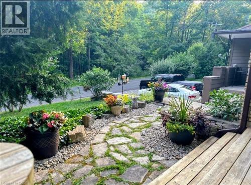 Stone pathway with gravel accents, leading to a front entrance with wooden steps - 1333 Hidden Valley Road, Burlington, ON - Outdoor With Deck Patio Veranda