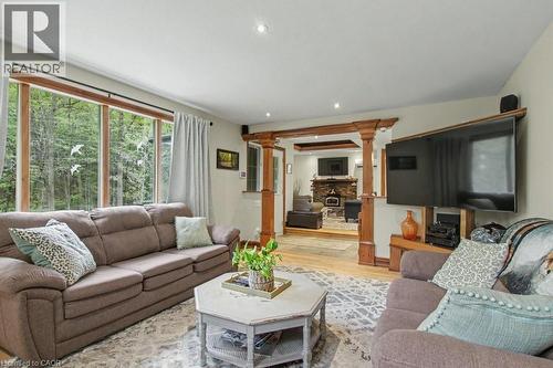 Living area featuring wood-frame windows, recessed lighting, wood-finish flooring, decorative wood columns, and a stone fireplace in the background - 1333 Hidden Valley Road, Burlington, ON - Indoor Photo Showing Living Room