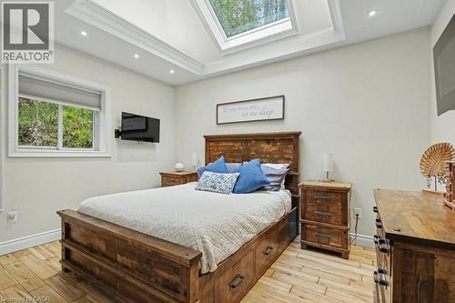 Recessed ceiling lighting and a large skylight illuminate this room, featuring wood-finish flooring and a window with roller shades - 1333 Hidden Valley Road, Burlington, ON - Indoor Photo Showing Bedroom
