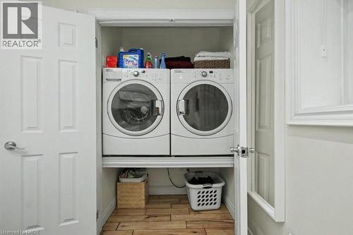 Dedicated laundry closet featuring a front-loading washer and dryer, wood-finish flooring, and white paneled doors - 1333 Hidden Valley Road, Burlington, ON - Indoor Photo Showing Laundry Room