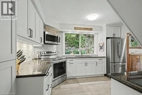 Modern kitchen featuring white cabinetry, dark countertops, and stainless steel appliances - 1333 Hidden Valley Road, Burlington, ON - Indoor Photo Showing Kitchen