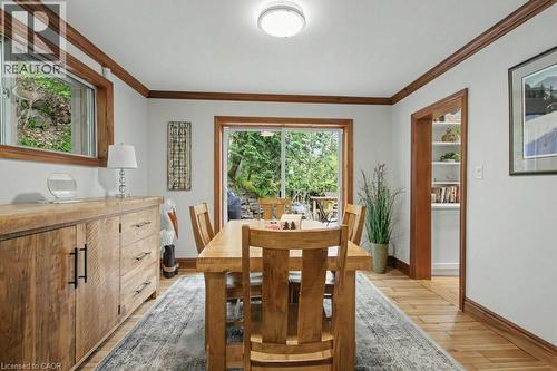 Dining space with light wood-finish flooring, wood trim, and a glass-paneled sliding door opening to exterior landscaping - 1333 Hidden Valley Road, Burlington, ON - Indoor Photo Showing Dining Room