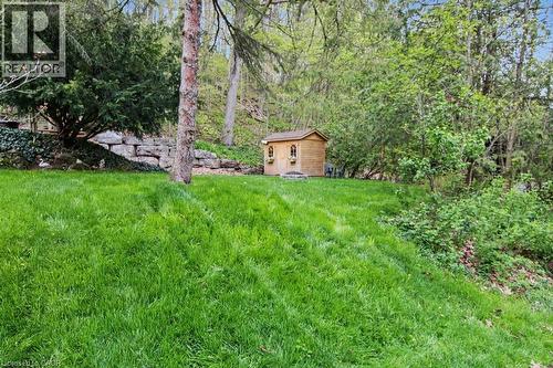 Expansive green lawn with a charming wooden shed featuring decorative windows - 1333 Hidden Valley Road, Burlington, ON - Outdoor