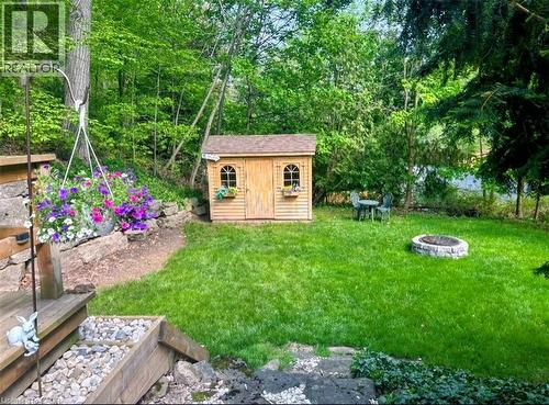 Spacious backyard with a stone fire pit, a natural wood storage shed, and mature trees providing natural screening - 1333 Hidden Valley Road, Burlington, ON - Outdoor
