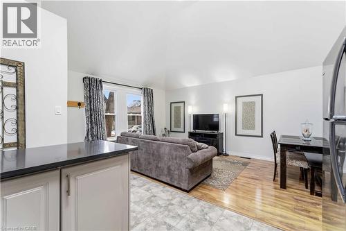 Open-concept living space featuring vaulted ceilings, wood-finish flooring, and white painted walls - 74 Province Street N, Hamilton, ON - Indoor Photo Showing Living Room
