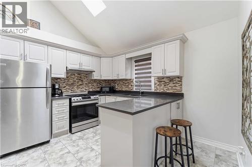 Kitchen featuring white shaker-style cabinetry, stainless steel appliances, a mosaic tile backsplash, dark countertops, and a skylight - 74 Province Street N, Hamilton, ON - Indoor Photo Showing Kitchen With Stainless Steel Kitchen With Upgraded Kitchen