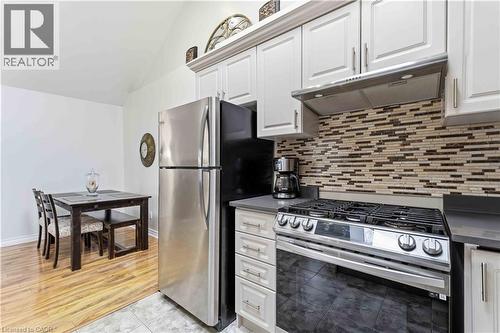 Kitchen featuring white cabinetry, grey countertops, stainless steel appliances, and a mosaic tile backsplash - 74 Province Street N, Hamilton, ON - Indoor Photo Showing Kitchen With Stainless Steel Kitchen