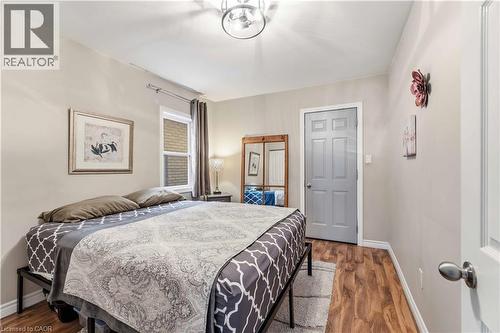 Bedroom featuring wood-finish flooring, neutral wall tones, a paneled door, a single window, and an overhead semi-flush mount light fixture - 74 Province Street N, Hamilton, ON - Indoor Photo Showing Bedroom