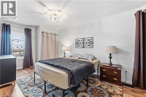 Bright interior space featuring wood-finish flooring, a window with exterior visibility, and a contemporary ceiling light fixture - 74 Province Street N, Hamilton, ON - Indoor Photo Showing Bedroom