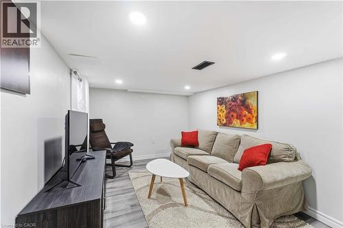 Recessed lighting illuminates this living space featuring light gray walls, wood-finish flooring, a white trim package, and a ceiling-mounted ventilation register - 74 Province Street N, Hamilton, ON - Indoor Photo Showing Basement