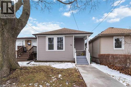 Single-story residence featuring light gray siding, a covered porch entry, and a gabled roof with brown shingles - 74 Province Street N, Hamilton, ON - Outdoor