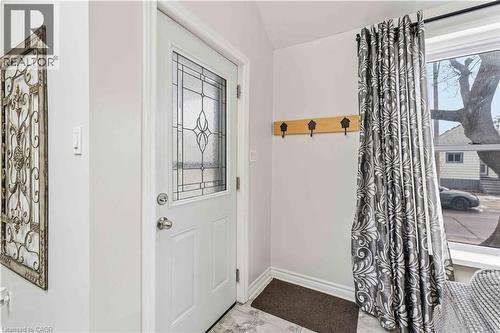 Entryway featuring a white door with decorative glass inserts, light grey wall paint, and wood-finish wall hooks - 74 Province Street N, Hamilton, ON - Indoor Photo Showing Other Room