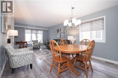 Open-concept dining area featuring a chandelier, wood-finish flooring, and a large window with horizontal blinds - 70 Queen Charlotte Crescent, Kitchener, ON - Indoor Photo Showing Dining Room