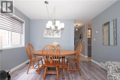 Dining area featuring wood-finish flooring, a contemporary chandelier, and a large window with privacy blinds - 70 Queen Charlotte Crescent, Kitchener, ON - Indoor Photo Showing Dining Room
