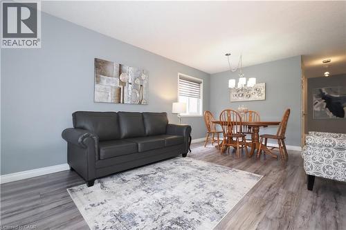 Open concept living and dining area featuring light gray walls, wood-finish flooring, a window with horizontal blinds, and a multi-light chandelier - 70 Queen Charlotte Crescent, Kitchener, ON - Indoor Photo Showing Living Room