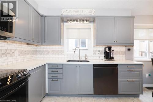 Contemporary kitchen featuring gray shaker-style cabinetry, white subway tile backsplash with decorative accents, and light-toned countertops - 70 Queen Charlotte Crescent, Kitchener, ON - Indoor Photo Showing Kitchen With Upgraded Kitchen