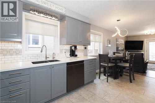 Modern kitchen featuring gray cabinetry, a double basin sink with a gooseneck faucet, white subway tile backsplash with accent detailing, and light-toned flooring - 70 Queen Charlotte Crescent, Kitchener, ON - Indoor Photo Showing Kitchen With Double Sink With Upgraded Kitchen