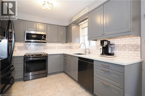 Contemporary kitchen featuring gray shaker-style cabinetry, white subway tile backsplash with decorative accents, and light-toned countertops - 70 Queen Charlotte Crescent, Kitchener, ON - Indoor Photo Showing Kitchen With Upgraded Kitchen